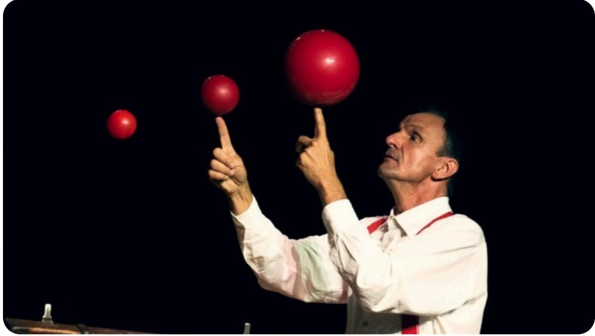 Artista de circo a equilibrar bolas vermelhas nos dedos