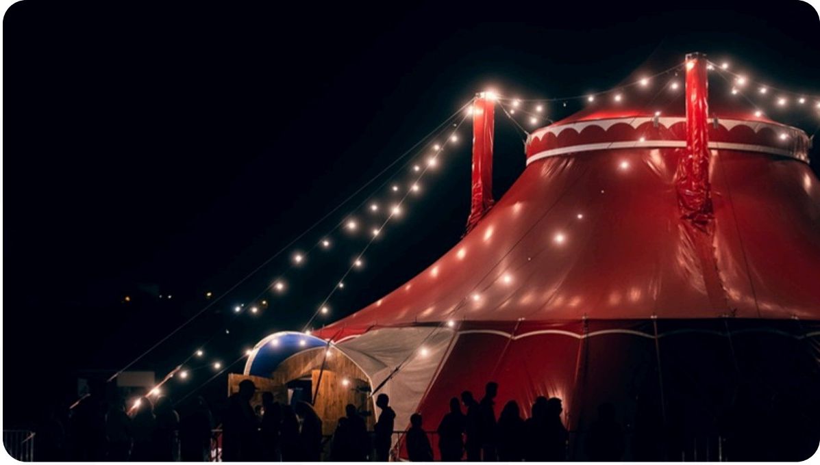 Tenda de circo vermelha iluminada à noite com público
